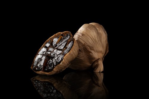 Black garlic on dark background. Culinary delicacy.