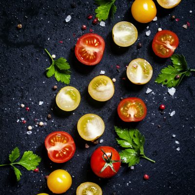 Food background: red, yellow and orange cherry tomatoes, black background